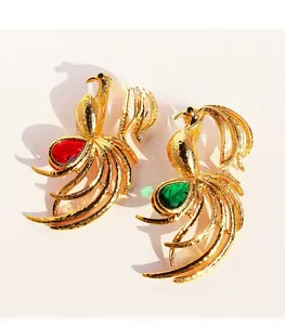 Detailed view of gold-plated phoenix brooches with pear-cut red and green cubic zirconia