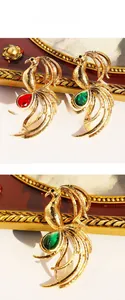 Detail of phoenix brooch with water drop red and green gemstones on textured gold metal