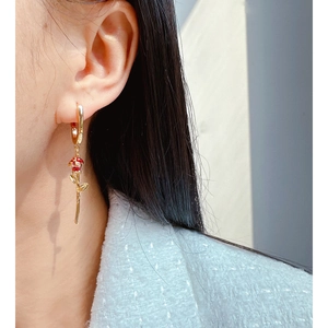 Elegant gold U-shaped hoop earrings with red enamel rose pendant worn by a model