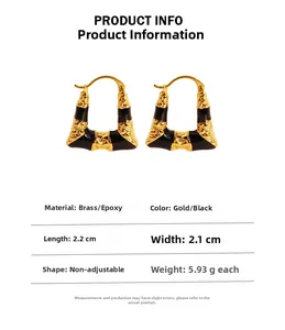 Vue détaillée des boucles d'oreilles trapèze montrant l'émail noir et la texture laiton