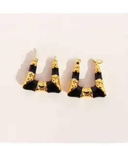 Détail de boucles d'oreilles trapèze en laiton avec émail noir et placage doré fin