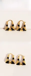 Détail macro de boucles d'oreilles trapèze dorées avec émail noir et texture vintage