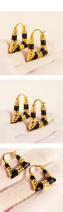 Détail de boucles d'oreilles trapèze vintage avec émail noir et textures plissées dorées