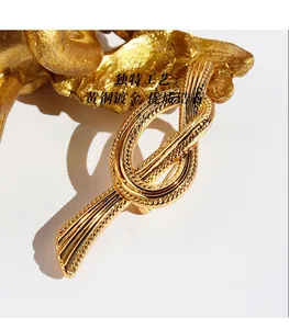 Macro shot of gold-plated brass ribbon knot brooch with clear texture and zircon
