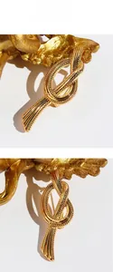 Detailed view of the knotted gold-plated brass brooch with spiral texture and glossy finish
