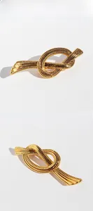 Macro detail of gold-plated brass ribbon knot brooch featuring fine textured engraving