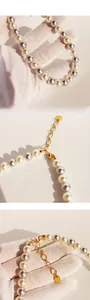 Détails d'un collier de perles grises et blanches avec un fermoir mousqueton doré chic