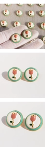 Macro detail of round pink tulip enamel earrings with golden frame and light green borders