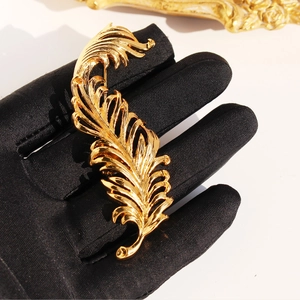 Exquisite gold-plated feather brooch with 3D texture on a black velvet glove backdrop