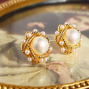 Vintage French pearl stud earrings with twisted gold edge on a retro frame background
