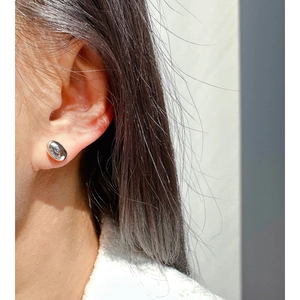 Minimalist silver bean stud earrings with polished mirror finish on model side view