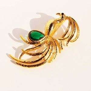 Elegant gold phoenix brooch with green emerald stone at a 45-degree angle