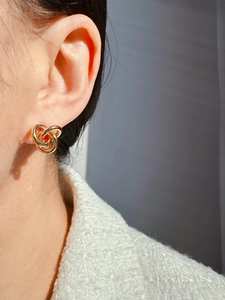 Nahaufnahme goldener Ohrstecker mit drei verschlungenen Ringen im Retro-Stil am Model