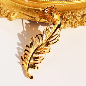 Detailed back view of a 3D gold-plated feather brooch with secure rotating safety pin clasp