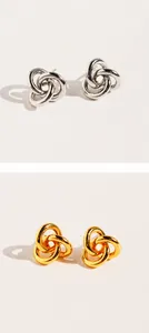 Makroaufnahme von ineinandergreifenden Dreifachschleifen-Ohrringen in Gold und Silber