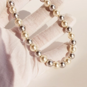 Collier vintage français avec perles rondes blanches et gris foncé tenu à la main