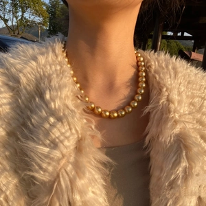 Elegant gold round pearl necklace set worn by a model in warm sunset lighting