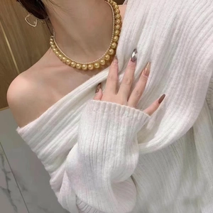 Close-up of elegant double-layered gold and white pearl necklace on a model wearing a sweater