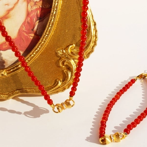 Parure en perles d'agate rouge avec nœuds dorés, comprenant collier et bracelet