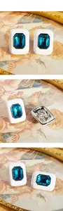 Macro shot of white enamel earrings featuring rectangular blue zircon and gold edges