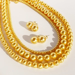 Lustrous gold pearl necklace and earring set with mirror-like metallic finish sheen