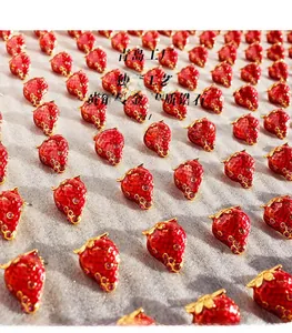 Detailed view of red strawberry earrings made of gold-plated brass and premium zircon