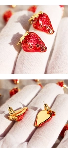 Detail of red enamel strawberry earrings with pink crystals and gold-plated backing
