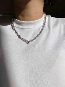 Dettaglio di una collana di perle e sfere d'argento indossata da una modella al sole