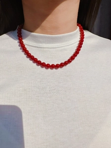 Close-up of red agate beaded necklace on a model wearing a white ribbed turtleneck sweater