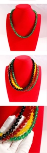 Detail of colorful beads on red display featuring green yellow and black glossy necklace