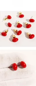 Macro detail of red oval cherry-style enamel stud earrings with gold plating