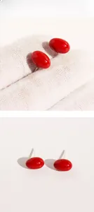 Macro detail of glossy red cherry-shaped enamel stud earrings with silver pins