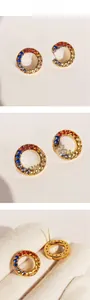 Detail view of round gold earrings with rainbow cubic zirconia and pin back closure