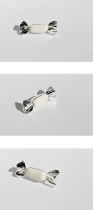 Macro view of a cream enamel candy-shaped brooch with silver twisted metal ends