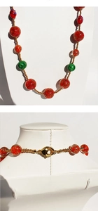 Details einer Vintage-Perlenkette mit roten Glasperlen und goldenem Karabinerverschluss