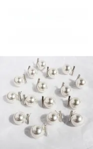 Close-up of pearl earrings with silver metal bars on white textured background