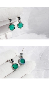 Dettaglio macro di orecchini verde smeraldo con montatura a griffe in metallo argento
