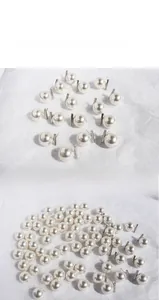 Macro shot of large lustrous white pearls on silver needles with a clean minimalist aesthetic