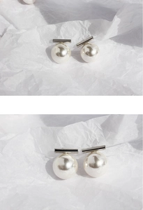 Macro detail of high-luster large pearl earrings with minimalist silver bar design