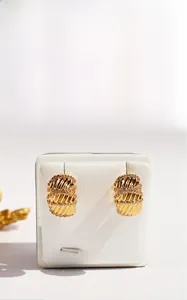 Close-up of gold-plated wave-textured hoop earrings with micro-inlaid zircon stones