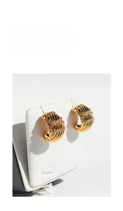 Macro detail of gold-plated wavy textured wide hoop earrings with micro-pave white zircons