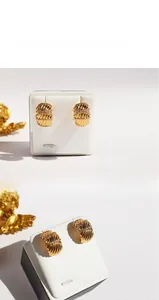 Detailed view of wide gold-plated wavy textured earrings with inlaid white zircons