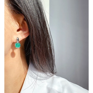 Orecchini a perno in argento con zircone verde rotondo mostrati per un look elegante