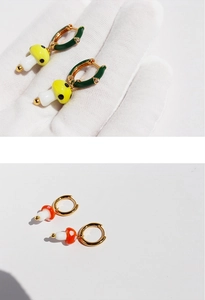 Dettaglio macro degli orecchini a cerchio con funghi a pois in smalto rosso e giallo