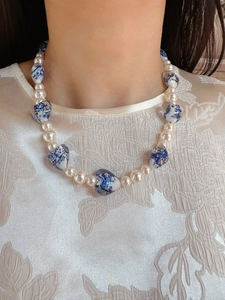 Detailed view of pearl necklace featuring blue and white porcelain heart pendant on a model