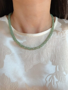 Dettaglio della collana di giada verde chiaro a forma di bambù su seta indossata da modella