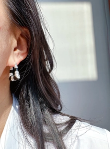 Gros plan sur une boucle d'oreille en U argentée avec émail noir et texture écailles