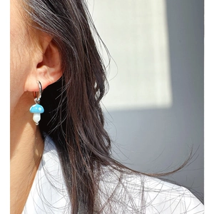 Orecchino a cerchio in metallo lucido con ciondolo a fungo blu a pois su modella