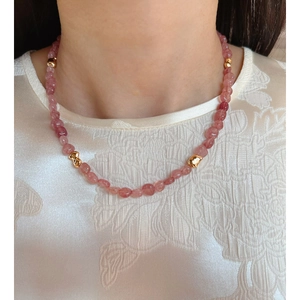 Collar de cuentas de cuarzo fresa con detalles dorados usado por una modelo