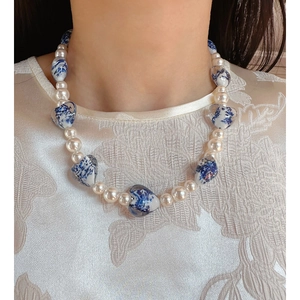 Vintage necklace with white pearls and blue and white porcelain heart charms worn by model